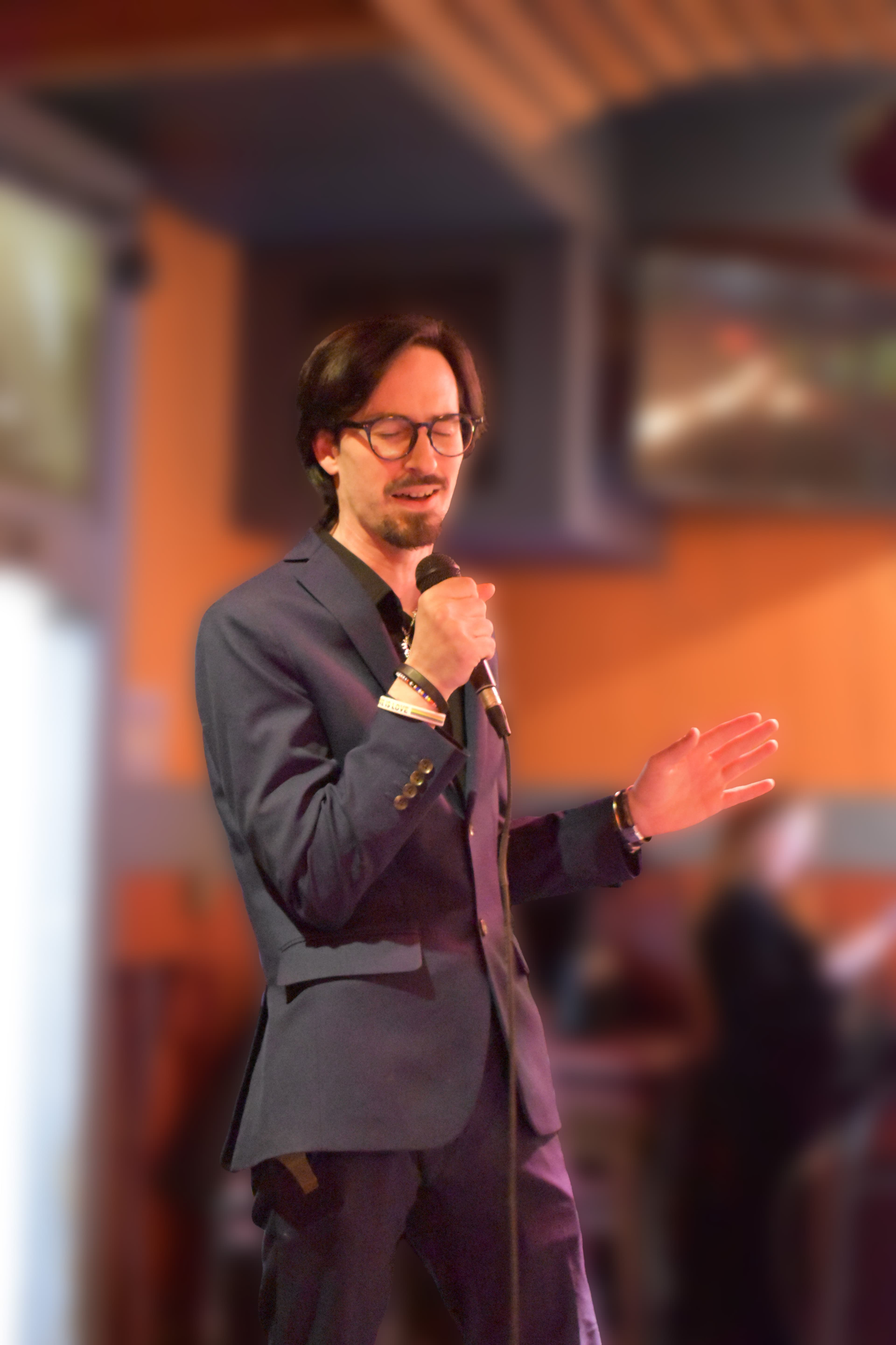 A man in a suit singing on stage.